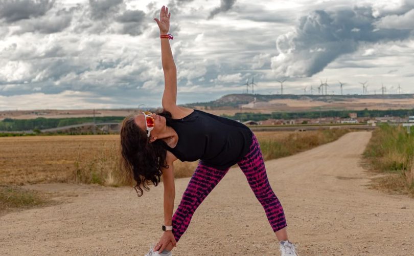 Outdoor fitness scene of a woman stretching on a dirt path in Soto de Cerrato amidst scenic landscapes.
